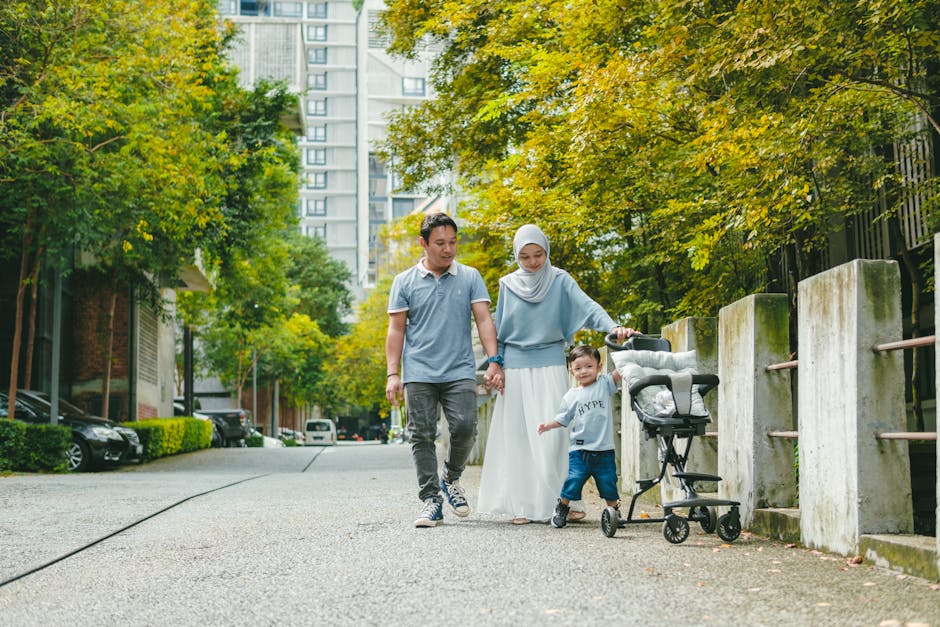 Happy family walking with a stroller in a city park enjoying fresh air