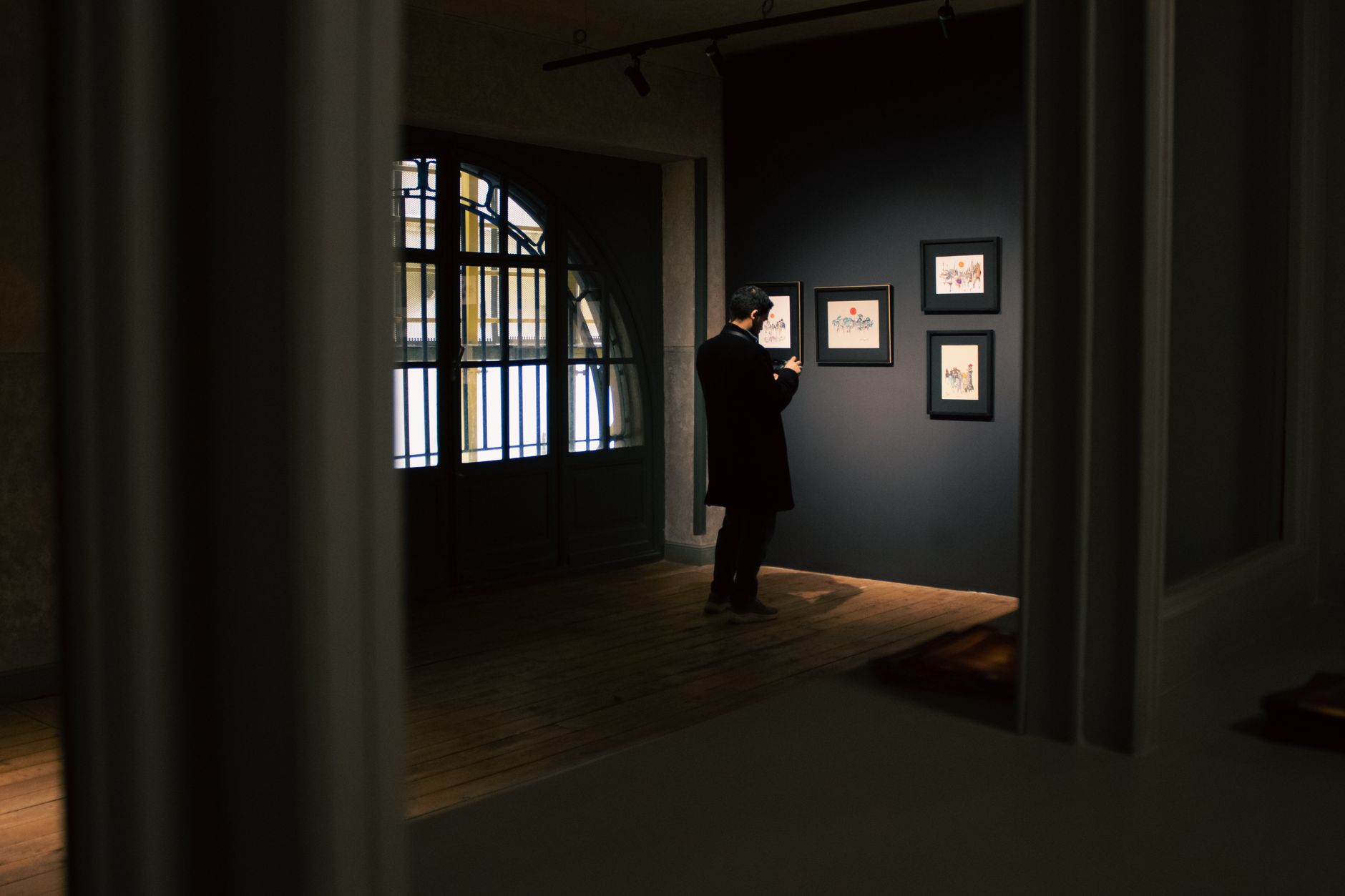 A visitor studying framed works in a quiet gallery room