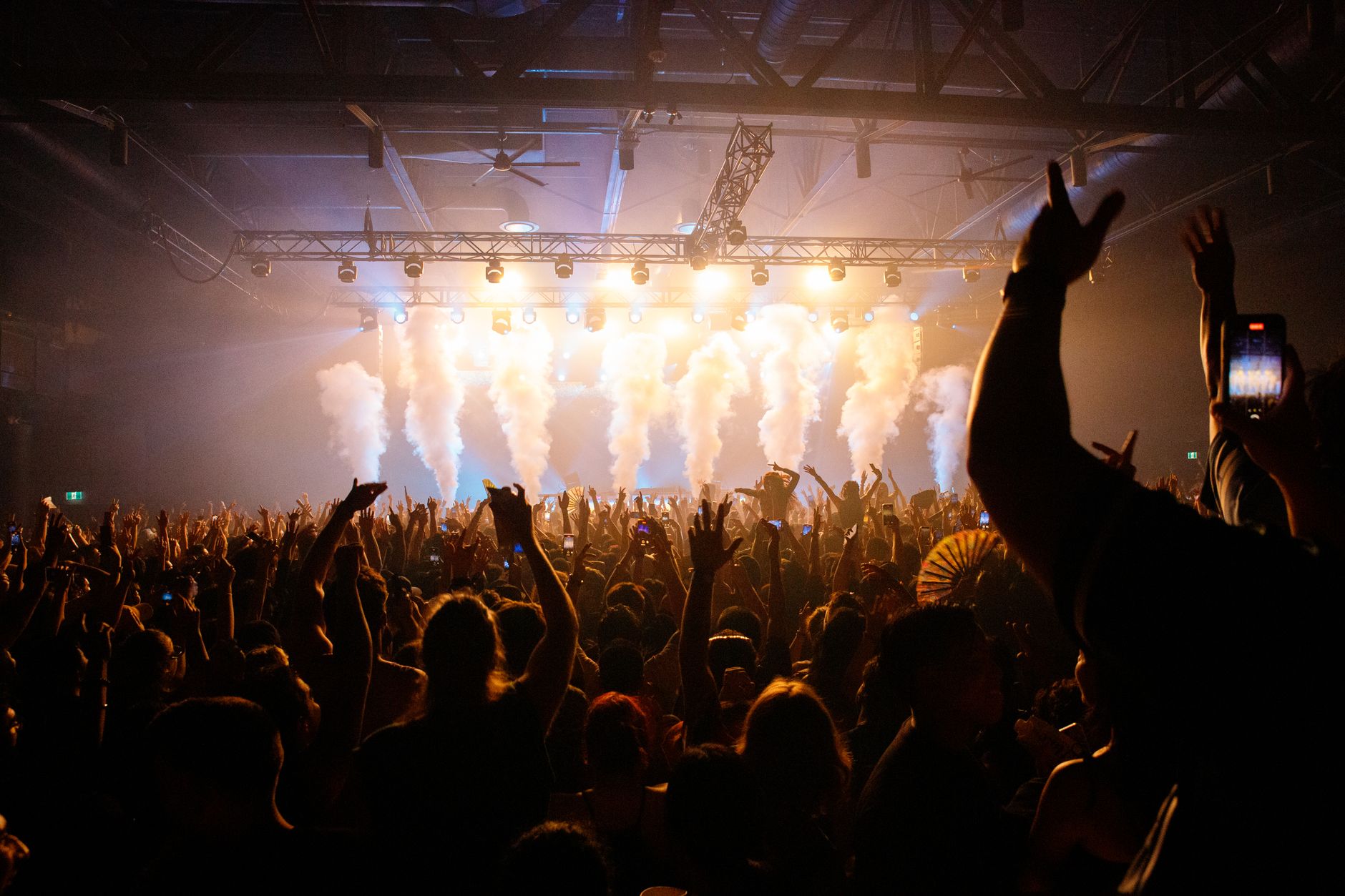 A crowd at a live music show with the stage lit behind them