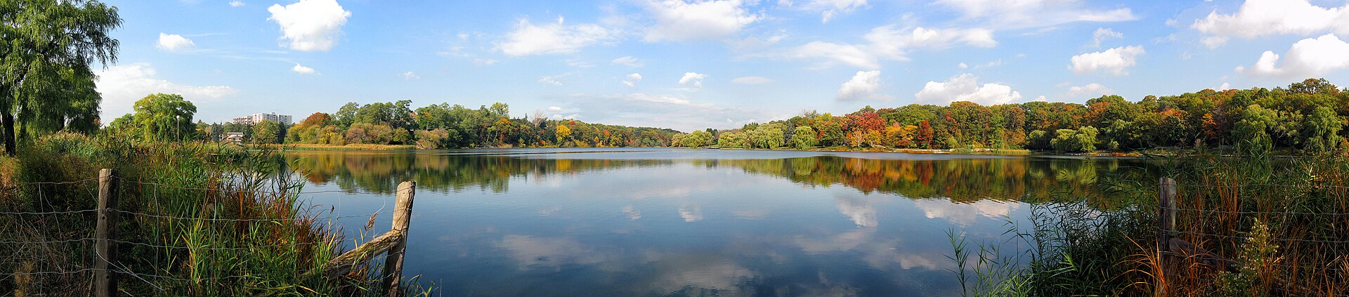 Wide autumn view across Grenadier Pond in High Park with colourful trees reflected in still water