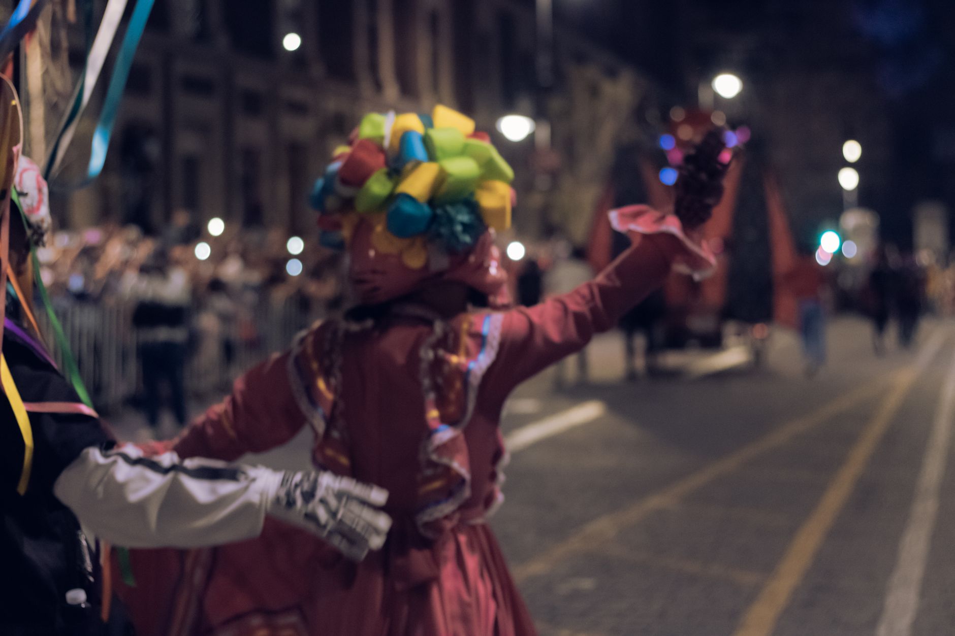 Crowd of people in costume filling a city street at night for a Halloween street party