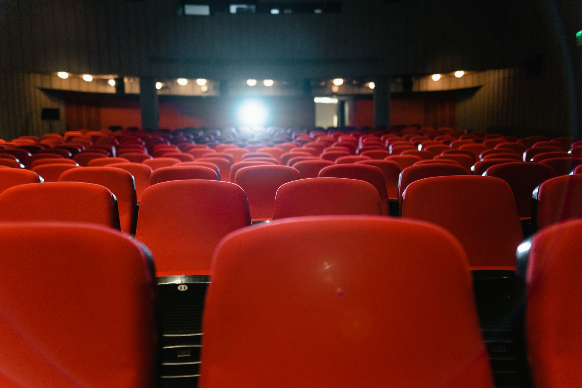 Dark cinema auditorium with rows of seats facing a glowing screen