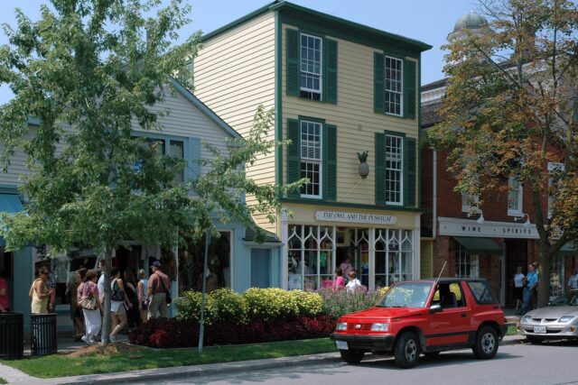 Historic clapboard shopfronts with green shutters and flower beds on Queen Street in Niagara-on-the-Lake