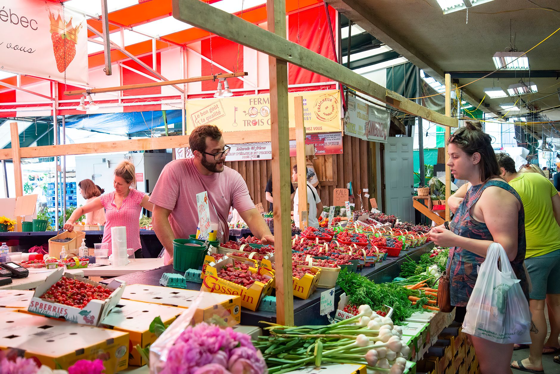 Produce and prepared-food stalls inside a covered farmers market, the morning stop on the itinerary