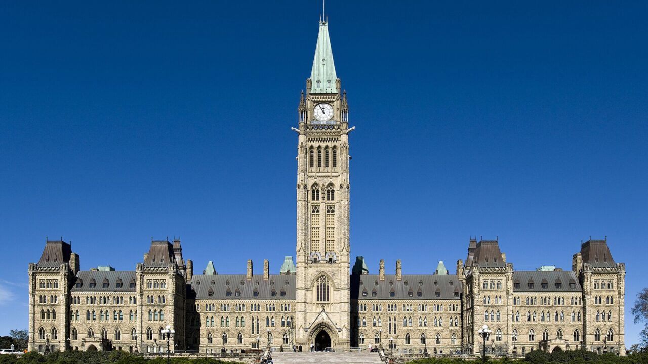 The Gothic Revival Centre Block of Canada's Parliament in Ottawa, with the Peace Tower rising in the middle under a deep blue sky