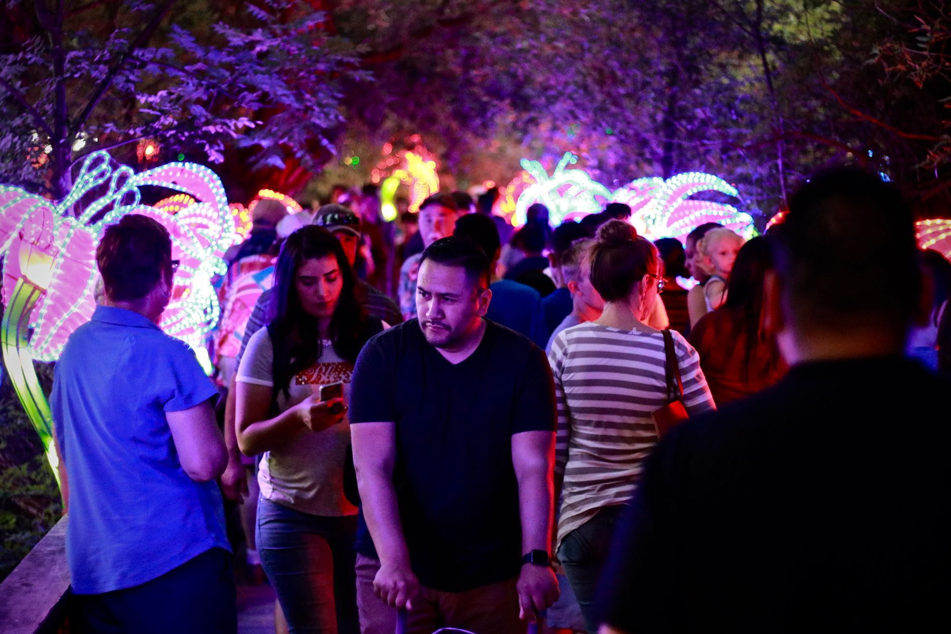 Crowd watching a large illuminated art installation in a city square during an all-night arts festival