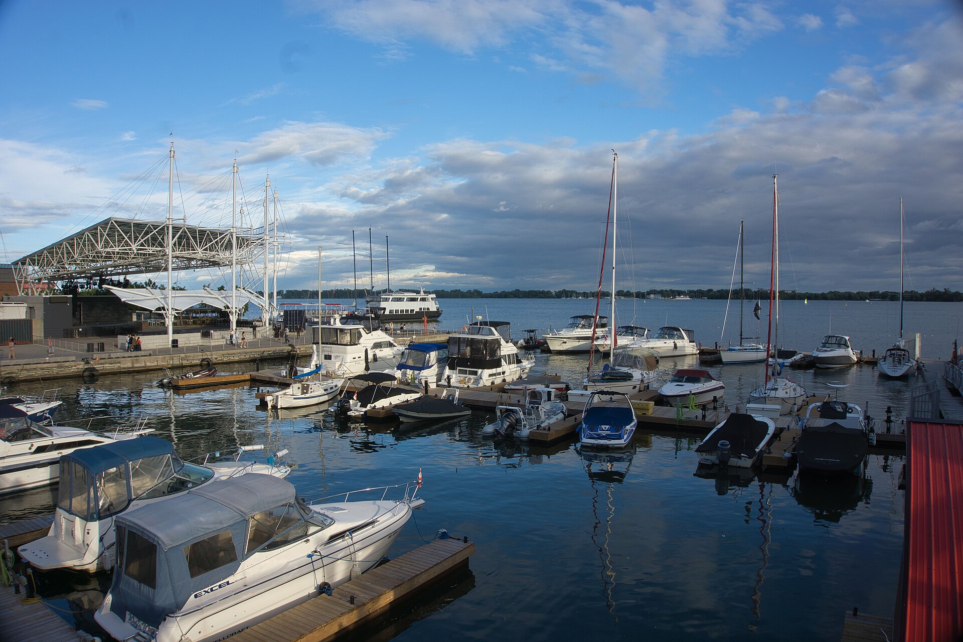 Marina full of moored boats at Toronto Harbourfront with a tour vessel and the Toronto Islands treeline behind