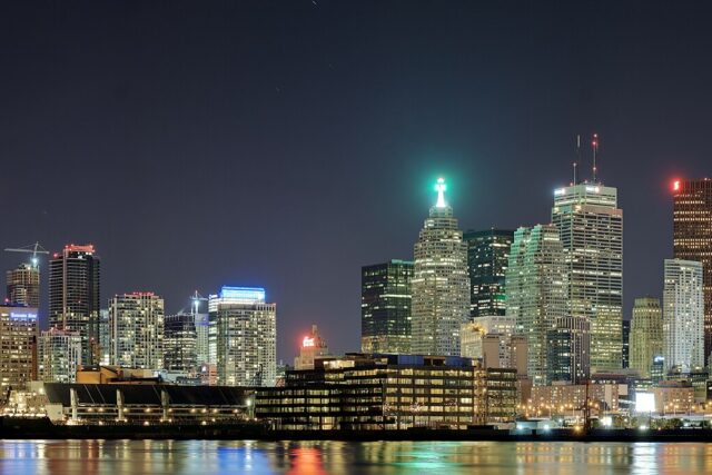 Toronto skyline at night seen across Lake Ontario with the CN Tower lit and reflections on the water