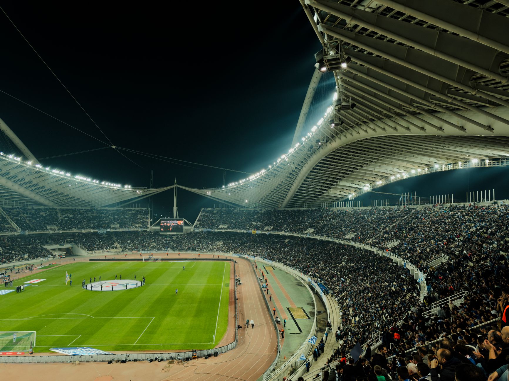 Packed soccer stadium under floodlights on a match night